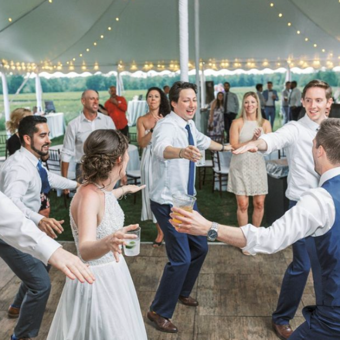 A group of people dance on the dance floor with drinks in hand.